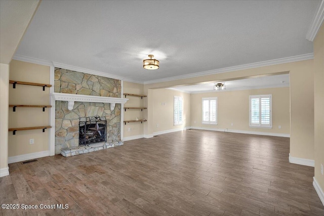 unfurnished living room with crown molding, a stone fireplace, a textured ceiling, and hardwood / wood-style flooring