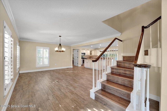 staircase featuring crown molding, wood-type flooring, an inviting chandelier, and a textured ceiling