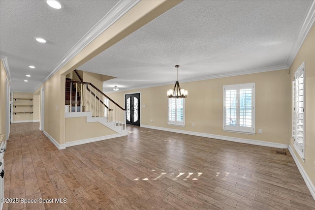 interior space featuring an inviting chandelier, hardwood / wood-style flooring, ornamental molding, and a textured ceiling