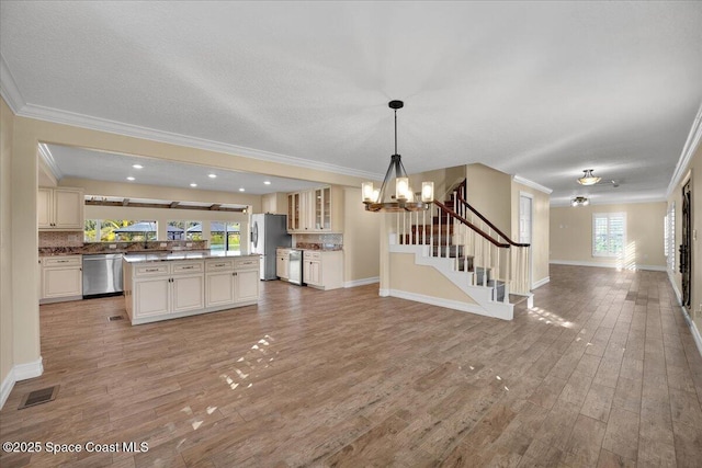 kitchen with a healthy amount of sunlight, stainless steel appliances, hanging light fixtures, and backsplash