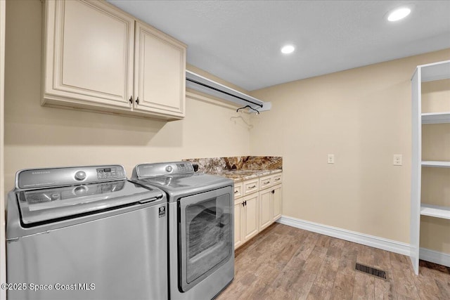 laundry room with cabinets, separate washer and dryer, and light hardwood / wood-style flooring