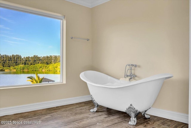 bathroom featuring hardwood / wood-style flooring, crown molding, and a tub to relax in