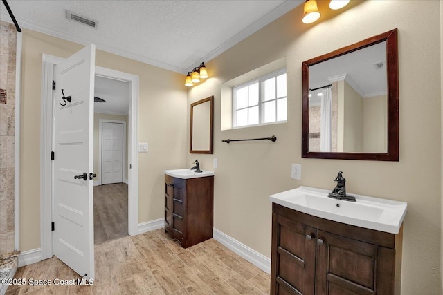 bathroom with crown molding, wood-type flooring, vanity, and a textured ceiling