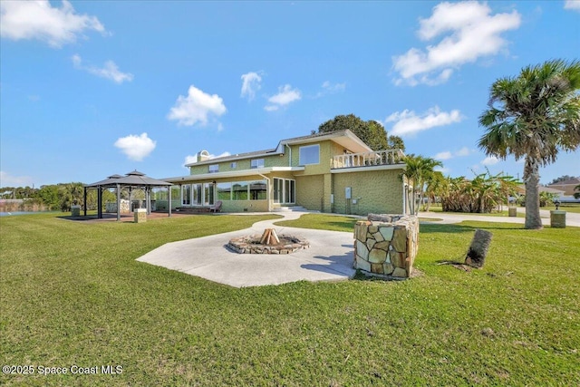 back of house featuring a gazebo, a yard, a patio, and a fire pit