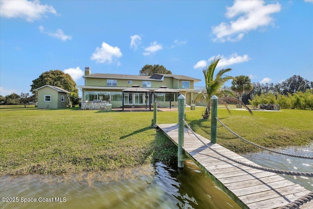 back of property with a gazebo, a water view, and a yard