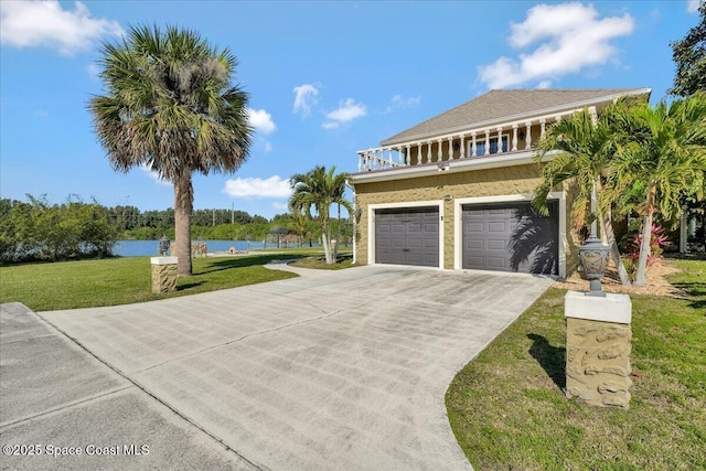 view of front facade with a garage, a balcony, a water view, and a front yard