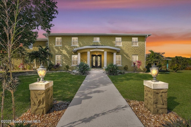 view of front facade with a yard and french doors