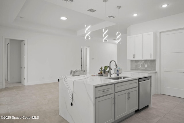 kitchen featuring dishwasher, a kitchen island with sink, sink, decorative light fixtures, and a raised ceiling