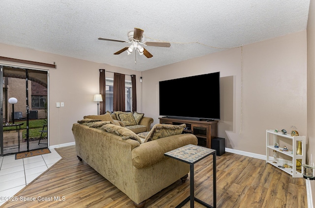 living room with ceiling fan, light hardwood / wood-style floors, and a textured ceiling