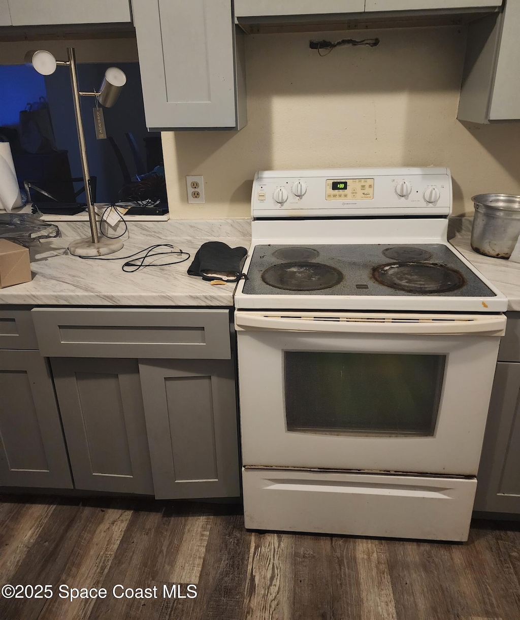 kitchen featuring gray cabinetry, dark hardwood / wood-style flooring, and white range with electric cooktop