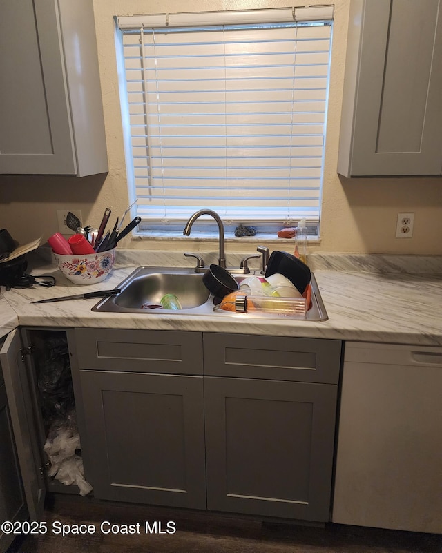 kitchen with sink, gray cabinetry, and white dishwasher