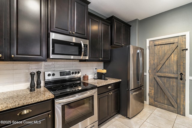 kitchen featuring light stone countertops, backsplash, appliances with stainless steel finishes, and light tile patterned flooring