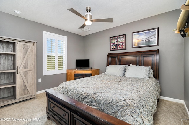 bedroom featuring light carpet, ceiling fan, and a barn door