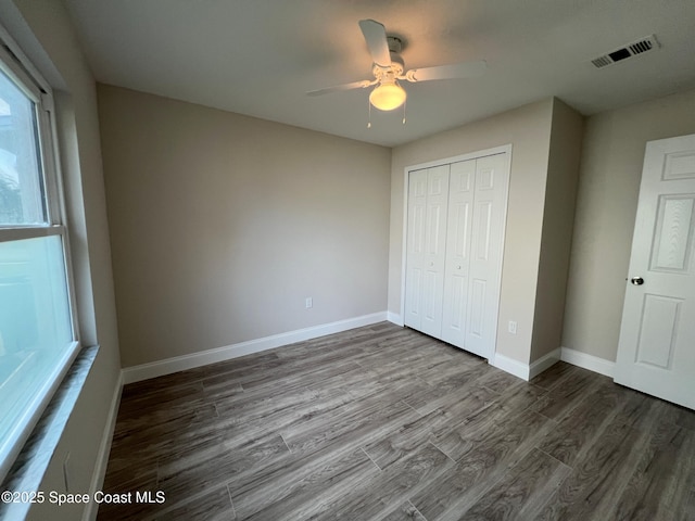 unfurnished bedroom featuring dark wood-type flooring, ceiling fan, and a closet