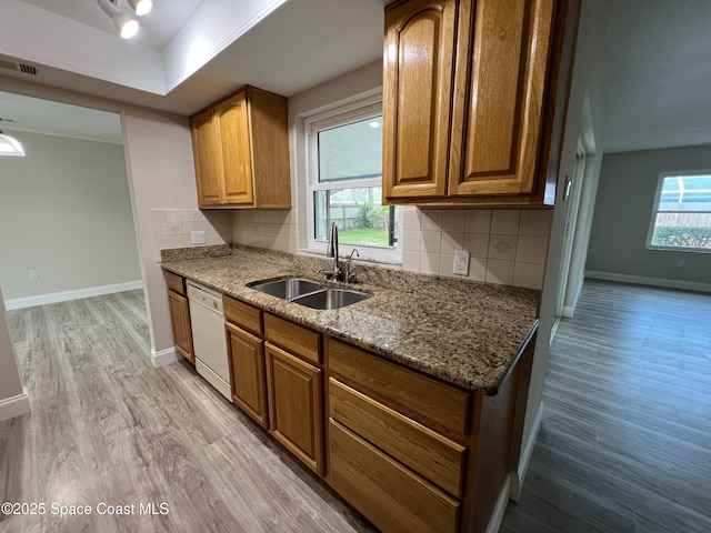 kitchen featuring white dishwasher, sink, light hardwood / wood-style floors, and a healthy amount of sunlight