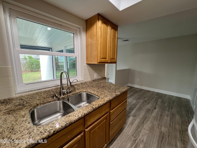 kitchen featuring sink, backsplash, light stone countertops, and dark hardwood / wood-style floors