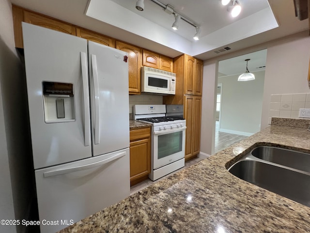 kitchen with a tray ceiling, sink, white appliances, and decorative backsplash