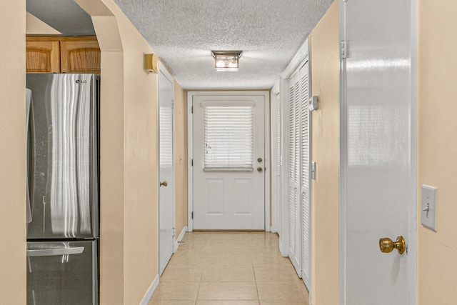 hallway featuring a textured ceiling and light tile patterned floors