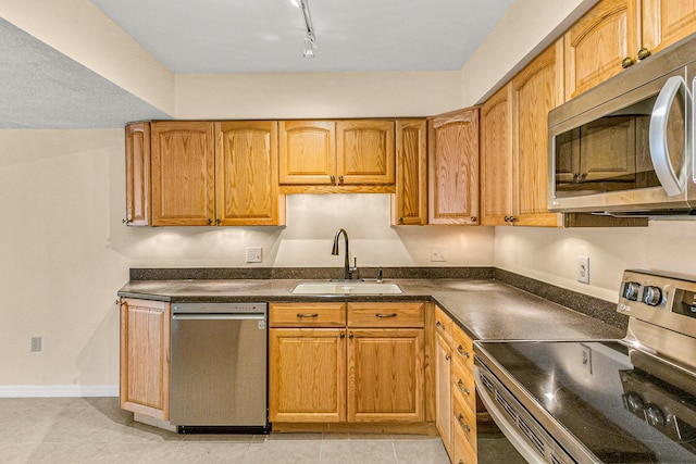 kitchen featuring light tile patterned floors, sink, appliances with stainless steel finishes, and track lighting