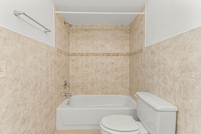 bathroom featuring tile walls, toilet, and tiled shower / bath combo