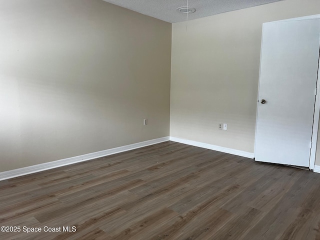 empty room featuring a textured ceiling and dark hardwood / wood-style floors