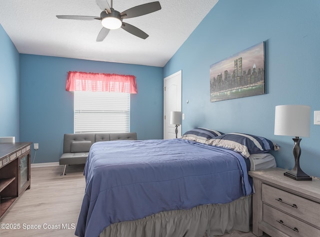 bedroom featuring ceiling fan, light hardwood / wood-style floors, a textured ceiling, and lofted ceiling