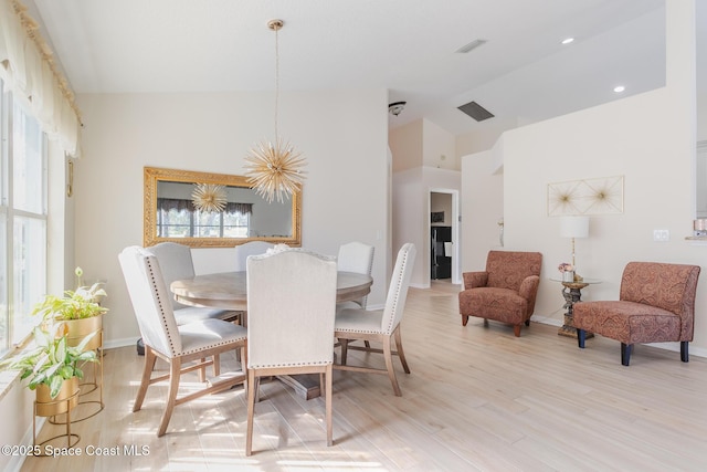 dining area featuring light wood-type flooring, a chandelier, and vaulted ceiling