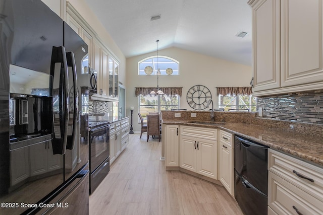 kitchen with sink, decorative light fixtures, dark stone countertops, black appliances, and lofted ceiling