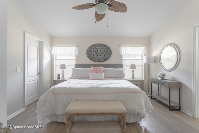 bedroom featuring light wood-type flooring, ceiling fan, and multiple windows