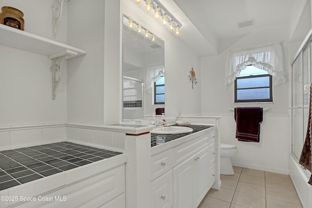 full bathroom with vanity, toilet, combined bath / shower with glass door, and tile patterned flooring