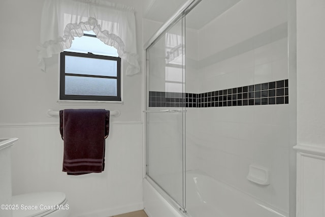 bathroom with toilet and combined bath / shower with glass door