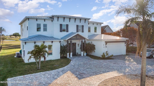 view of front of house with a garage, a front lawn, and central air condition unit