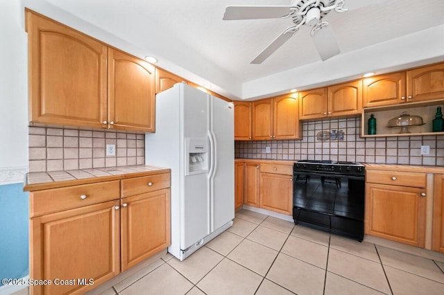 kitchen with backsplash, tile counters, light tile patterned floors, white refrigerator with ice dispenser, and black / electric stove