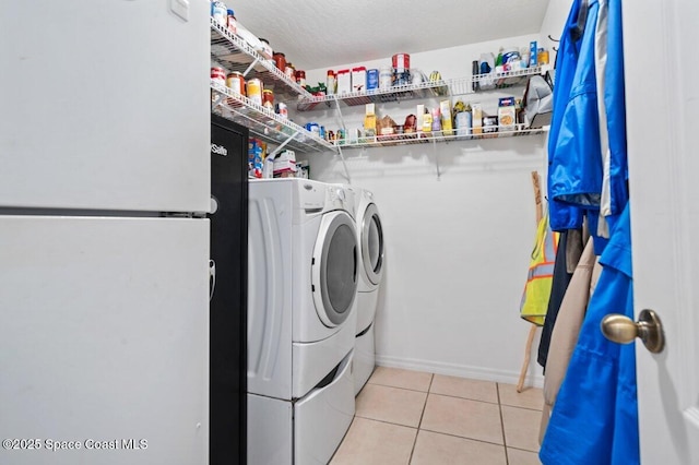 laundry room with baseboards, light tile patterned flooring, laundry area, and washer and clothes dryer