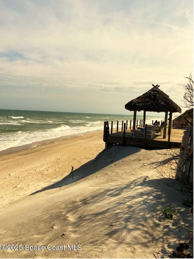 dock area featuring a gazebo, a water view, and a beach view