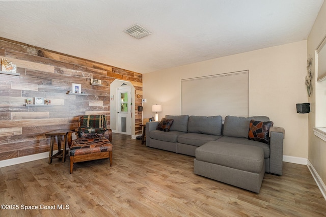 living room with light hardwood / wood-style floors and wood walls