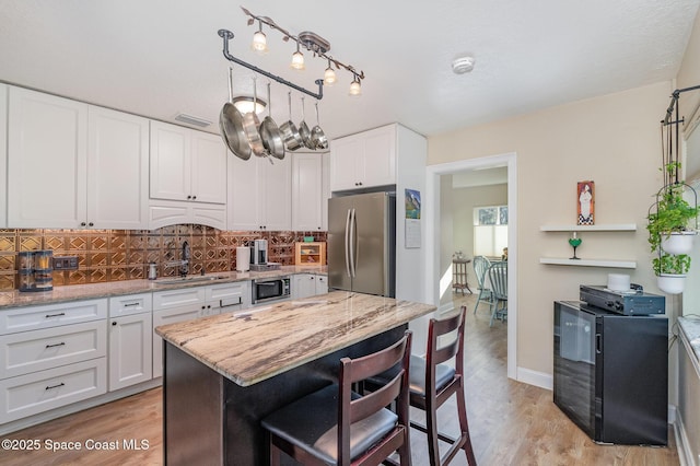 kitchen with sink, stainless steel appliances, white cabinets, and light stone countertops