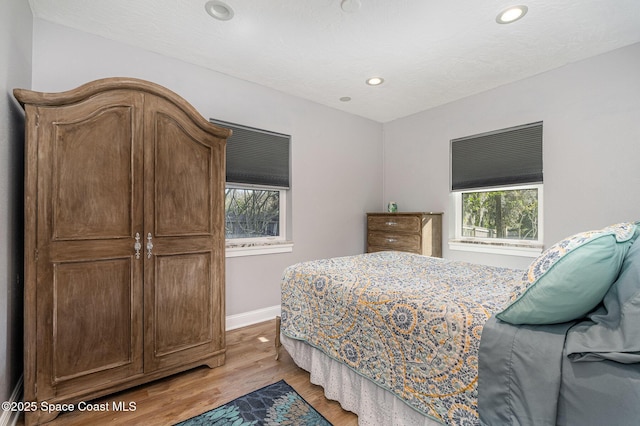 bedroom with multiple windows and light hardwood / wood-style flooring