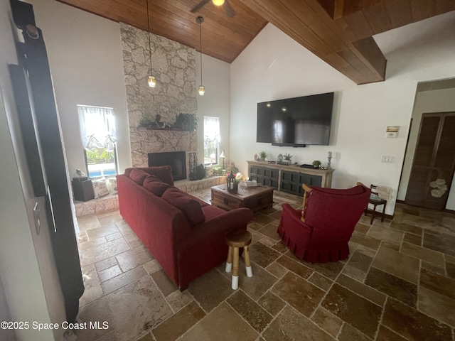 living room with stone tile floors, wood ceiling, a fireplace, high vaulted ceiling, and a wealth of natural light