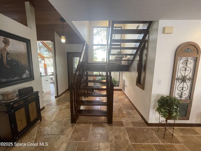 stairs with stone tile floors, baseboards, and a textured ceiling