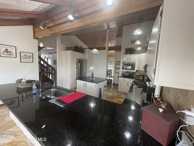 kitchen featuring lofted ceiling with beams, a peninsula, a kitchen island, a sink, and backsplash