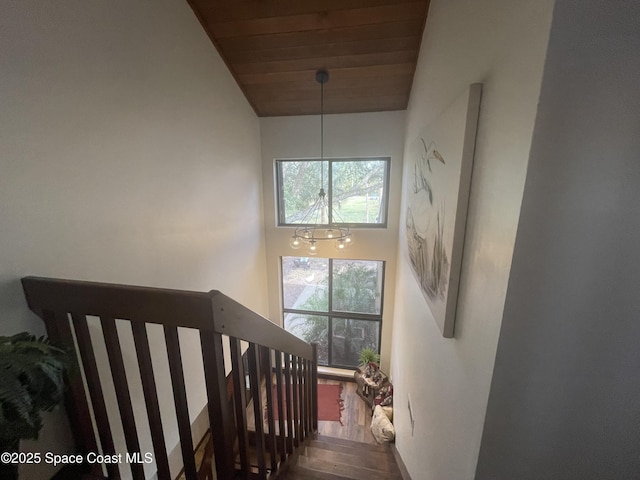 stairs with wooden ceiling, wood finished floors, and a towering ceiling