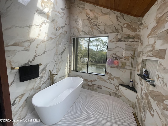 full bathroom with a freestanding tub, stone wall, walk in shower, and tile walls