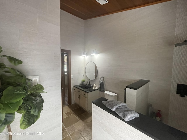 bathroom with tile walls, visible vents, wood ceiling, stone finish flooring, and vanity