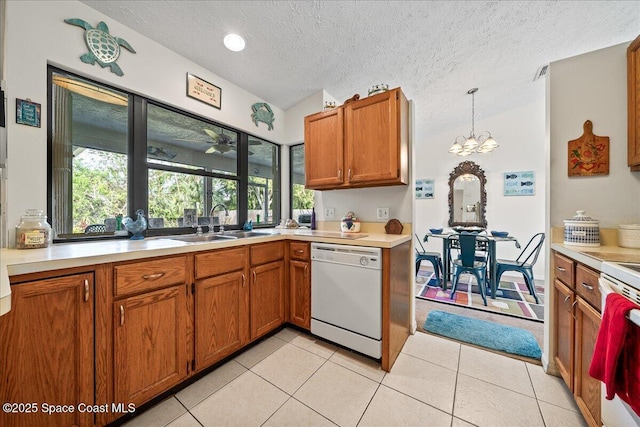 kitchen featuring hanging light fixtures, light tile patterned flooring, sink, and white dishwasher