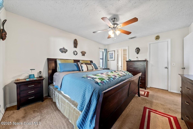 bedroom featuring light colored carpet, a textured ceiling, and ceiling fan