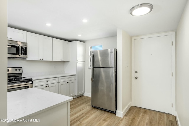 kitchen featuring white cabinets, stainless steel appliances, and light hardwood / wood-style flooring