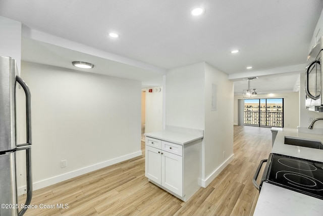 kitchen with appliances with stainless steel finishes, white cabinetry, sink, light wood-type flooring, and pendant lighting