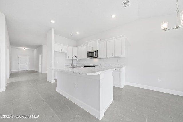 kitchen featuring sink, a kitchen island with sink, light tile patterned floors, and white cabinetry