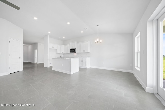 unfurnished living room with sink, light tile patterned flooring, a chandelier, and lofted ceiling